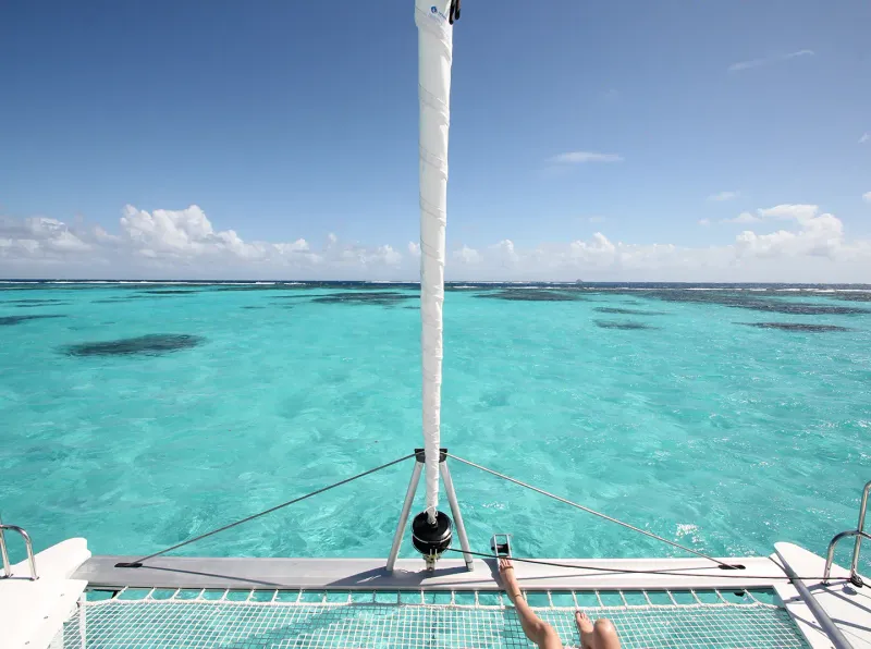 Catamaran cruising near lush green Caribbean islands at sunset
