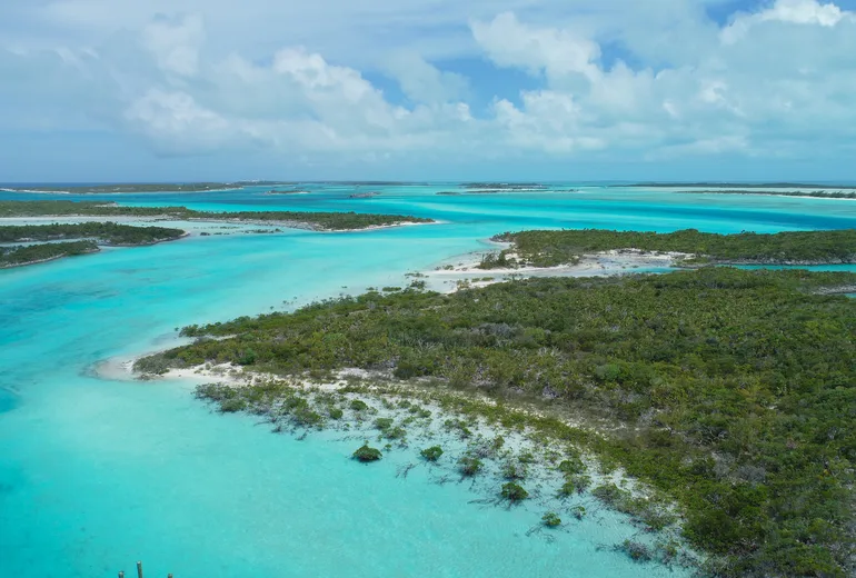 Aerial of low green cays and winding turquoise sand channels