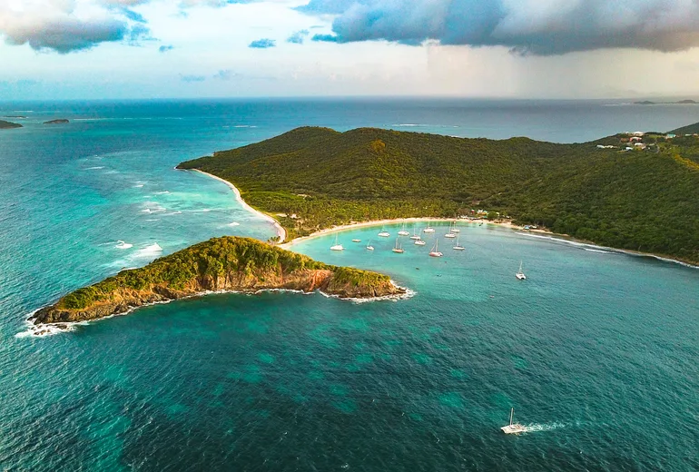 Aerial of Salt Whistle Bay on Mayreau, yachts behind a narrow palm spit in the Grenadines