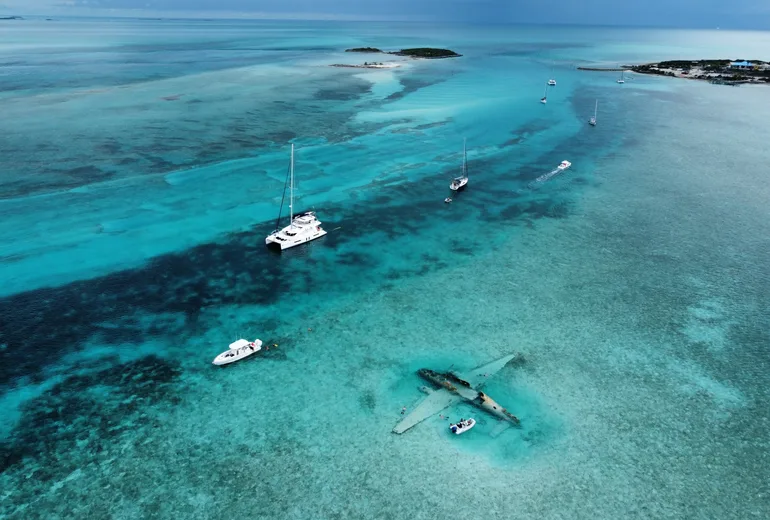 Aerial of the sunken plane wreck snorkelling site with anchored yachts in the Exumas