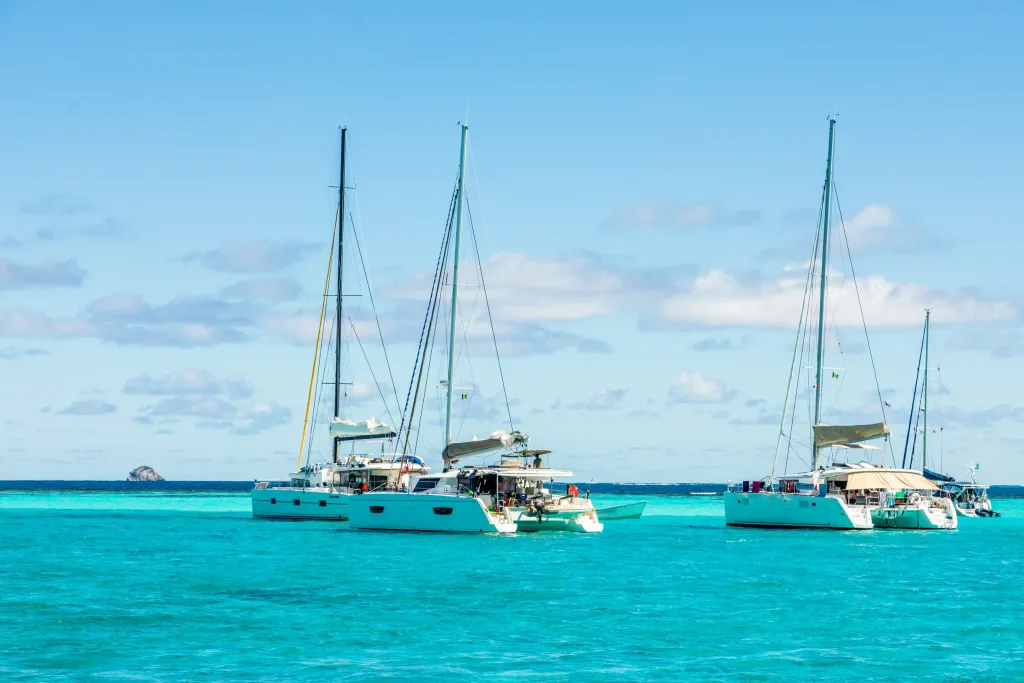Charter catamarans anchored in shallow turquoise water near reef