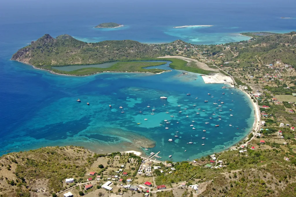 Aerial view of curved Caribbean bay with anchored yachts and reefs