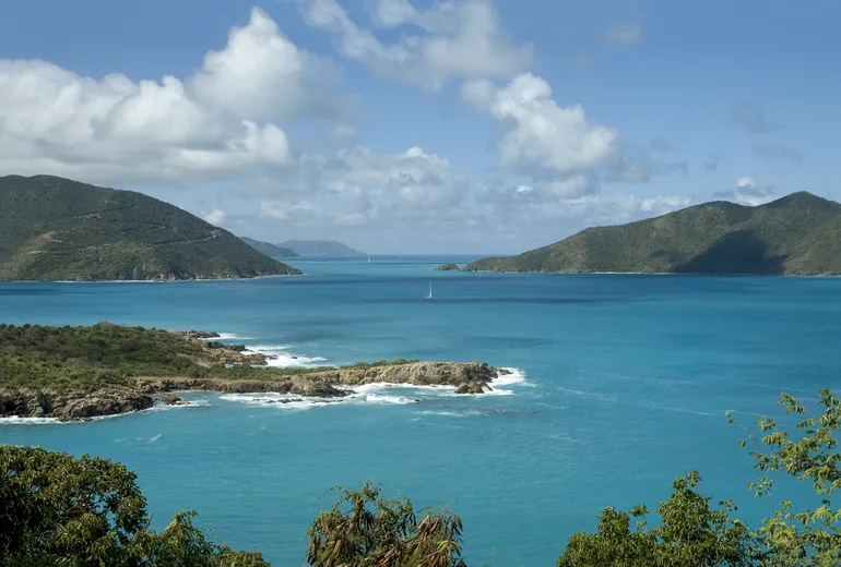 Lone sailboat in a calm turquoise channel in light air