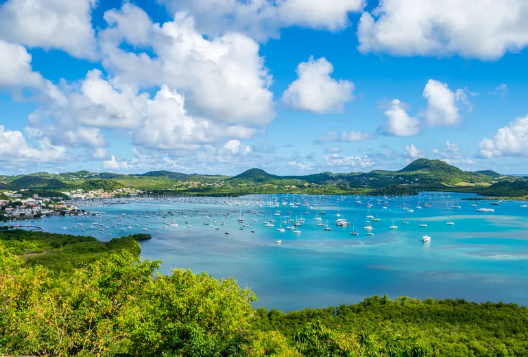 Sailboats at anchor in a wide Caribbean bay in summer haze