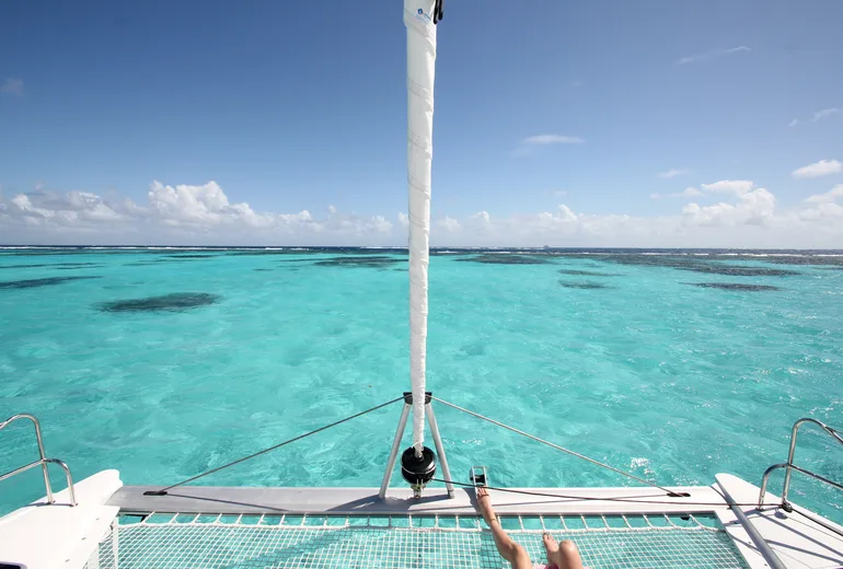 View from a catamaran bow trampoline over reef shallows